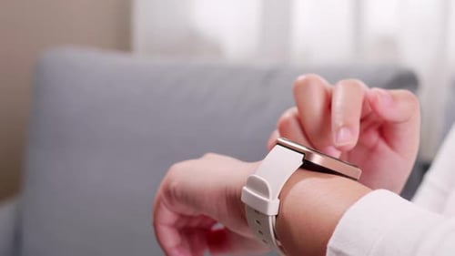 Close up of woman hands using a smart watch and doing application setting in the living room.