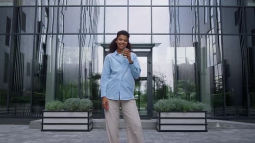 Pleased Businesswoman Posing Drinking Coffee Cup on Contemporary Office Facade