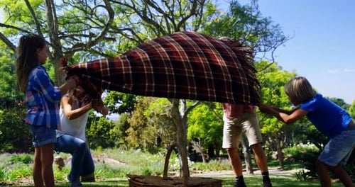 Family Setting Up Picnic Blanket in Garden