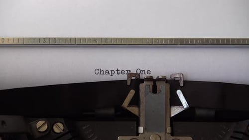 Typing phrase Chapter One on retro typewriter. Close up.
