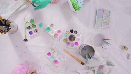 Flat lay. Little girl painting paper mache figurines with acrylic paint for her homeschooling art p