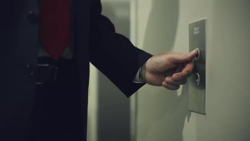 Geschäftsmann drückt roten Knopf zum Anrufen des Aufzugs im modernen Geschäftsbüro