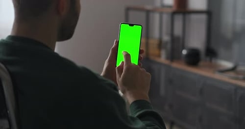 Man Is Swiping and Tapping on Touch Screen of Modern Smartphone Holding Gadget Vertically Green