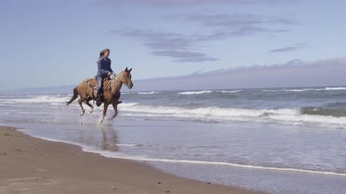 Women riding horses at beach in slow motion