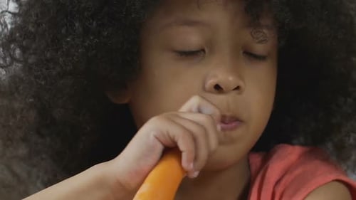 Adorable Girl Eating a Fresh Carrot Close Up