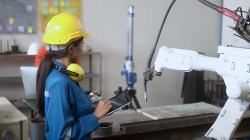 Technischer Ingenieur verwaltet die Tastatureingabe, programmiert die Bewegung des modernen Schweißroboterarms