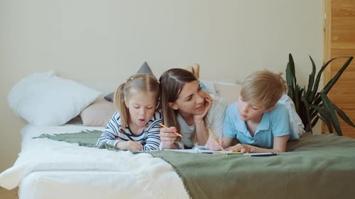 Mother and Children Drawing Together on Bed