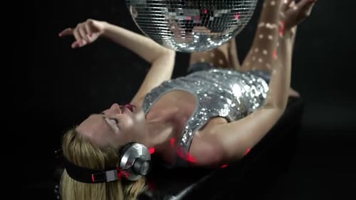 Woman Relaxes Under Disco Ball in Dark Room