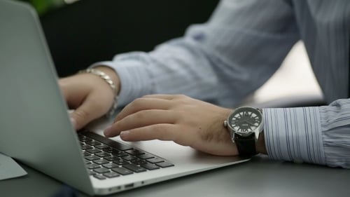 Man Typing on Laptop in Office Environment