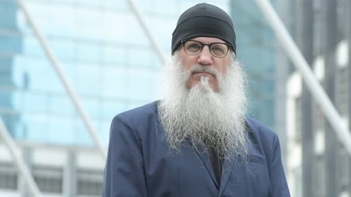 Face of Mature Bearded Businessman Wearing Beanie and Eyeglasses in the City Outdoors