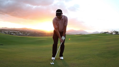 Golfer Performing Swing at Sunrise on Green Course