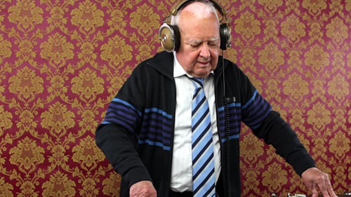 Senior Man Mixing Music on Turntable with Headphones