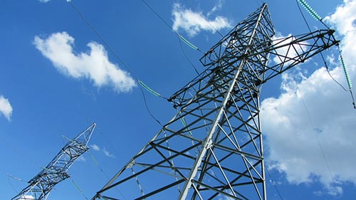 Tall Electric Masts Against Cloudy Sky