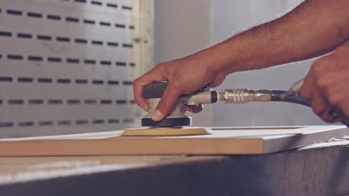 Slow motion of a worker polishing a cabinet door in a furniture factory