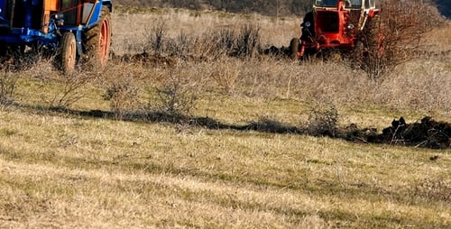 Tractors Plowing Grassy Field in Rural Setting