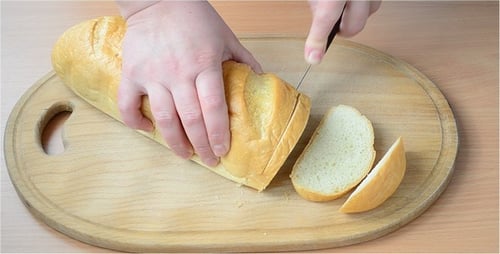 Baguette Being Sliced on Wooden Cutting Board