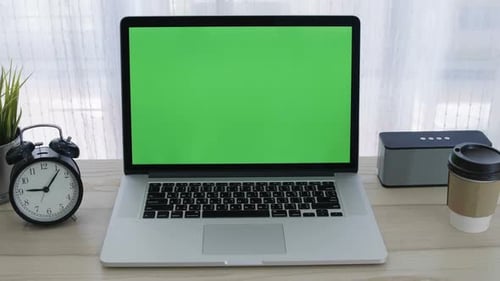 Chroma key green screen of laptop computer set on working space in home office