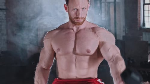 An Athletic Attractive Man Pumping His Hands Muscles with Dumbbells