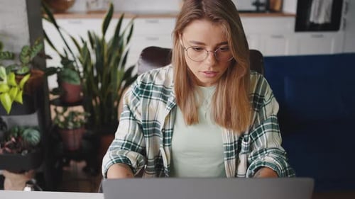 Top View on Young Concentrated Blonde Lady in Eyeglasses Working Remotely at Home Typing on Laptop
