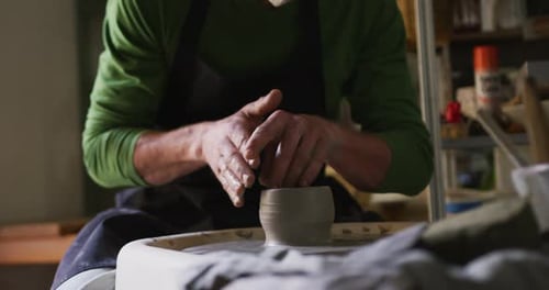 Section centrale d'un potier masculin créant de la poterie sur une roue de potier dans un atelier de poterie