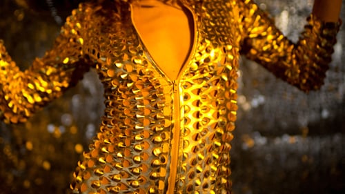 Glamorous Woman Dancing in Shiny Gold Outfit