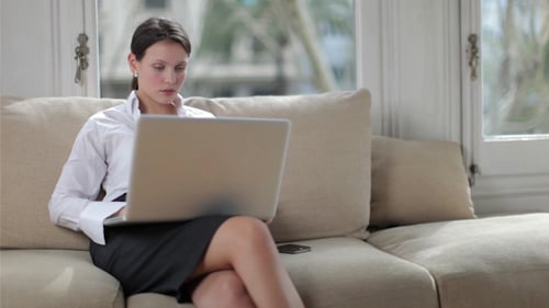 Woman Works on Laptop Computer While Sitting on Couch