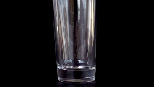 White Liquid Poured into Glass with Black Background