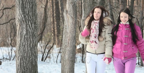 Two Young Women Walking in Snowy Winter Forest
