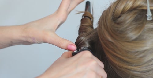 Friseur verdreht das Haar mit einem Lockenstab