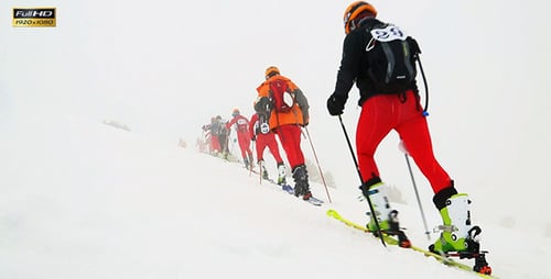 Skiers Climb Snowy Mountain in Winter Conditions