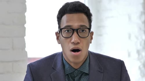 Close Up Of African Businessman Surprised By Results While Using Tablet