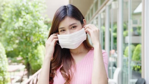 Woman Puts on Protective Face Mask Outdoors