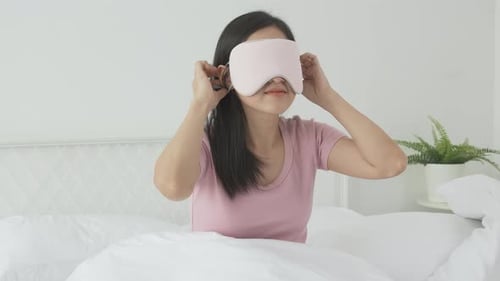 Beautiful young asian woman wearing cover eye and sleeping on bed with head on pillow comfort.