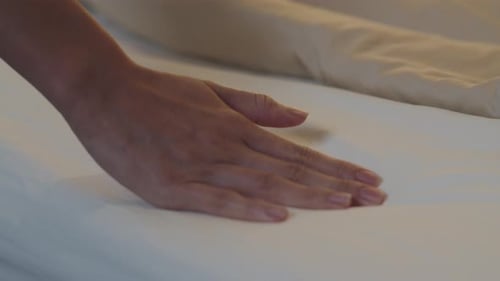 Hand Gently Pressing on Fresh White Bed Sheet