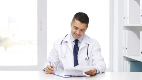 Happy Doctor With Clipboard In Hospital