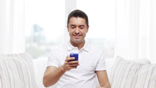 Man Smiling and Talking on Smart Phone Indoors