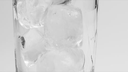 Ice Cubes Dropping into Clear Glass Close Up