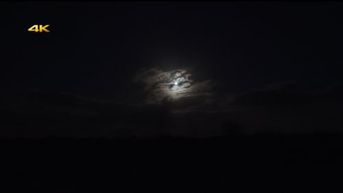 Moon Shining Through Dark Clouds in Night Sky