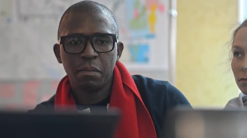 Multiethnic Man and Woman Are Talking and Using Laptops at Workplace in Modern Office Irrl.