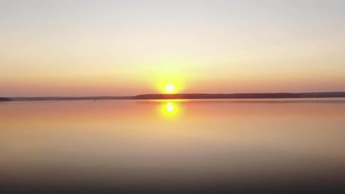 Stunning Aerial View of the Sunset Over a Huge Lake and the Reflection of the Pink Sky and Sun in