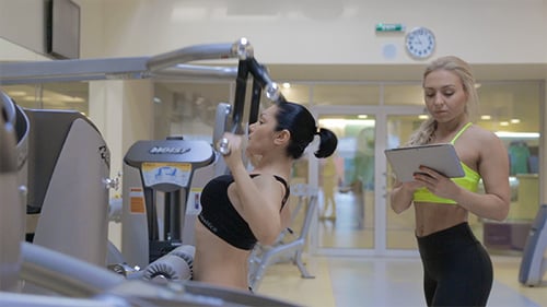 Woman Using Lat Pulldown Machine with Trainer