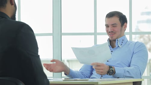 Smiling Man Discussing Documents in a Meeting