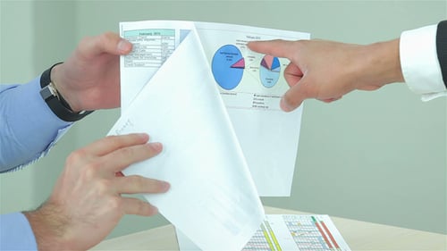 Hands Reviewing Charts and Graphs in Documents