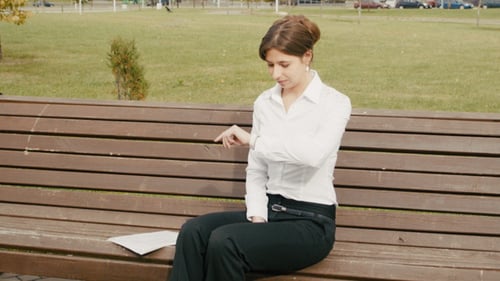 Woman Checks Watch Waiting on Park Bench