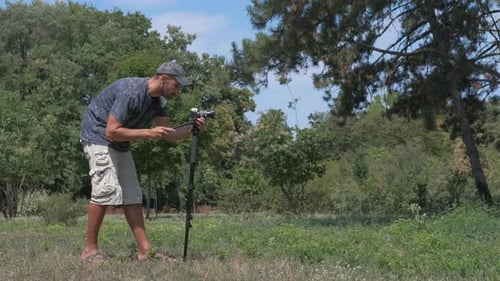 Man Using Camera Equipment in Rural Park