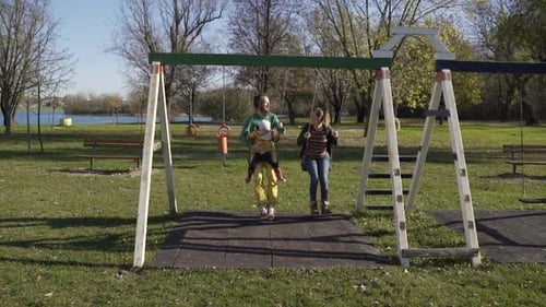 Family playing at swing in public playground, Zagreb, Croatia.