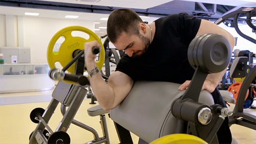 Muscular Man Working Out Biceps in Gym