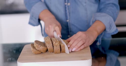 Person Slicing Bread on Cutting Board in Kitchen