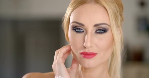 Blonde Woman with Makeup Touches Face