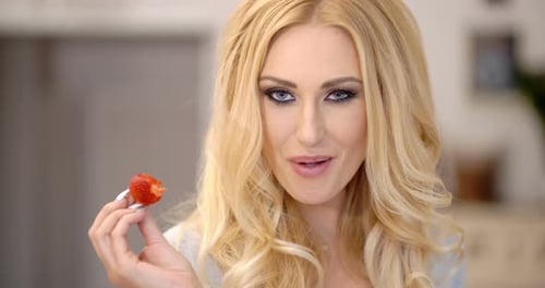 Mulher loira atraente saudável comendo um morango 2